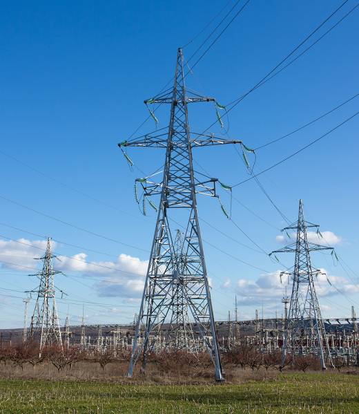 industrial landscape. High voltage towers with electrical wires on blue sky background. Electricity transmission lines, electric power station.